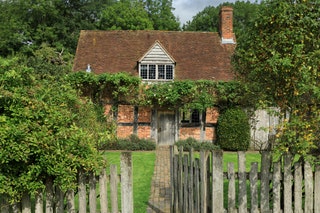 Image may contain Outdoors Cottage Housing House Building Roof Nature Fence Garden and Arbour